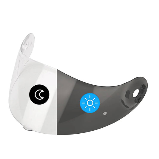 A photochromic visor for Nolan helmets, showing a clear upper half and a smoked lower half with a blue circular logo on the lower right corner.